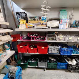 Stellingen met rode, groene en blauwe kunststof opbergbakken en kratten met gereedschap en onderdelen