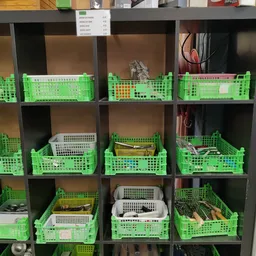 Stellingen met groene kunststof kratten gevuld met huishoudelijke artikelen en spullen