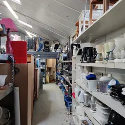 Winkelinterieur met stellingen vol huishoudelijke artikelen, apparaten en diverse goederen