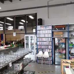 Winkelvloer met glazen toonbank, boekenrekken, stellingen met spullen en raam met veel daglicht