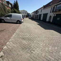 Straatfoto met geparkeerde witte bestelbus en historische witte gebouwen aan weerszijden