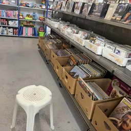 Kartonnen dozen met cd's en dvd's op de winkelbodem, stellingen met artikelen op de achtergrond