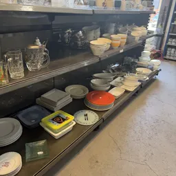 Uitgestalde serviesgoed, borden, schalen en glazen in een kringloopwinkel