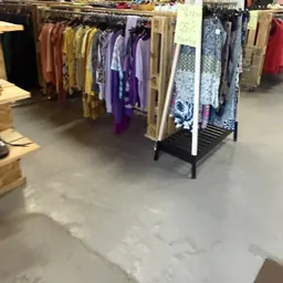 Kledingrekken met tweedehands kleding in verschillende kleuren, waaronder paars, geel en blauw