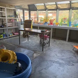 Werkruimte in kringloopwinkel met tafels, speelgoed en dozen bij ramen