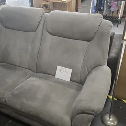 Grijze tweedehands fauteuil of loveseat met prijskaartje in kringloopwinkel