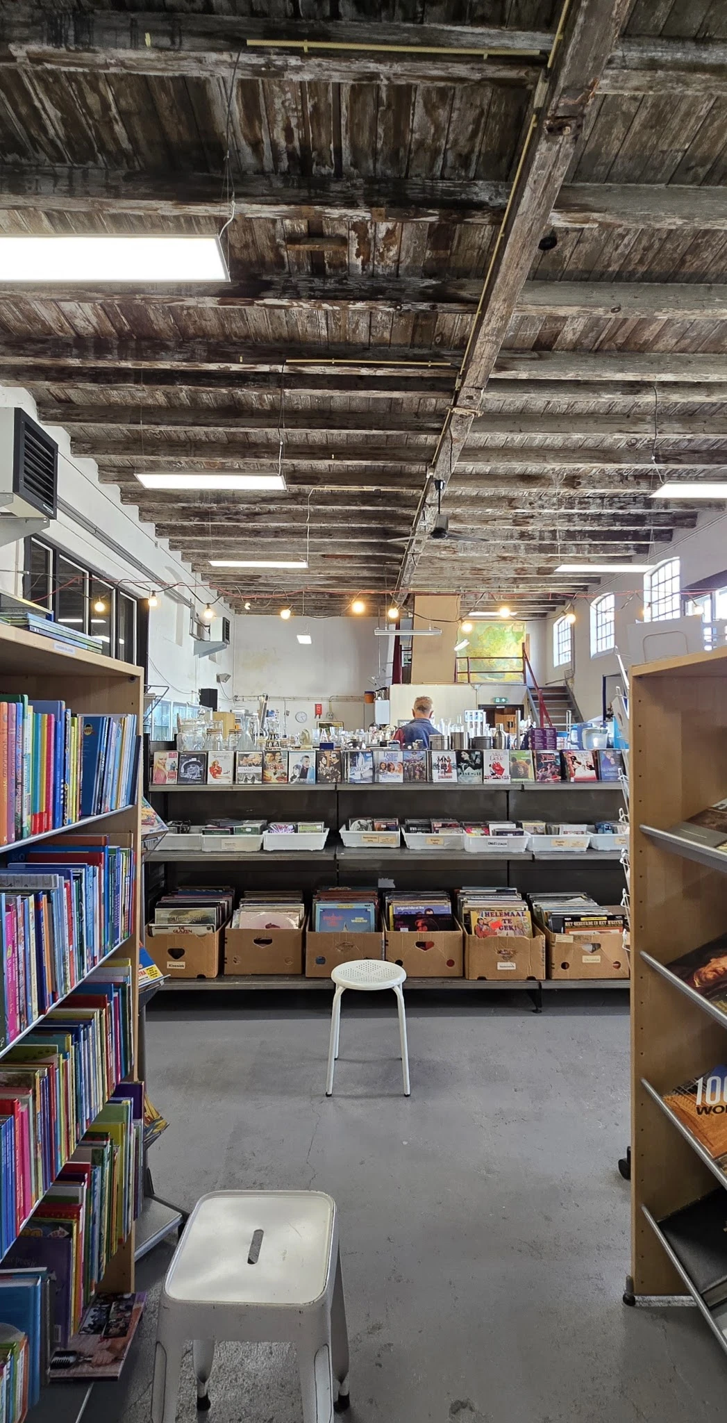 Uitgestalde tweedehands boeken, dvd's en media op stellingen en in dozen in de winkel