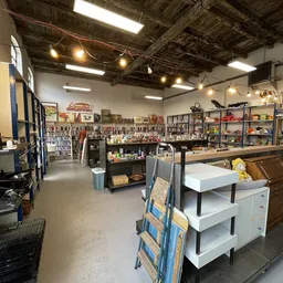Winkelvloer met stellingen vol spullen, toonbanken en diverse tweedehands artikelen in een ruime kringloopwinkel