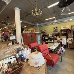 Winkelvloer met rode stoelen, houten meubels, serviesgoed en decoratieve artikelen in een kringloopwinkel