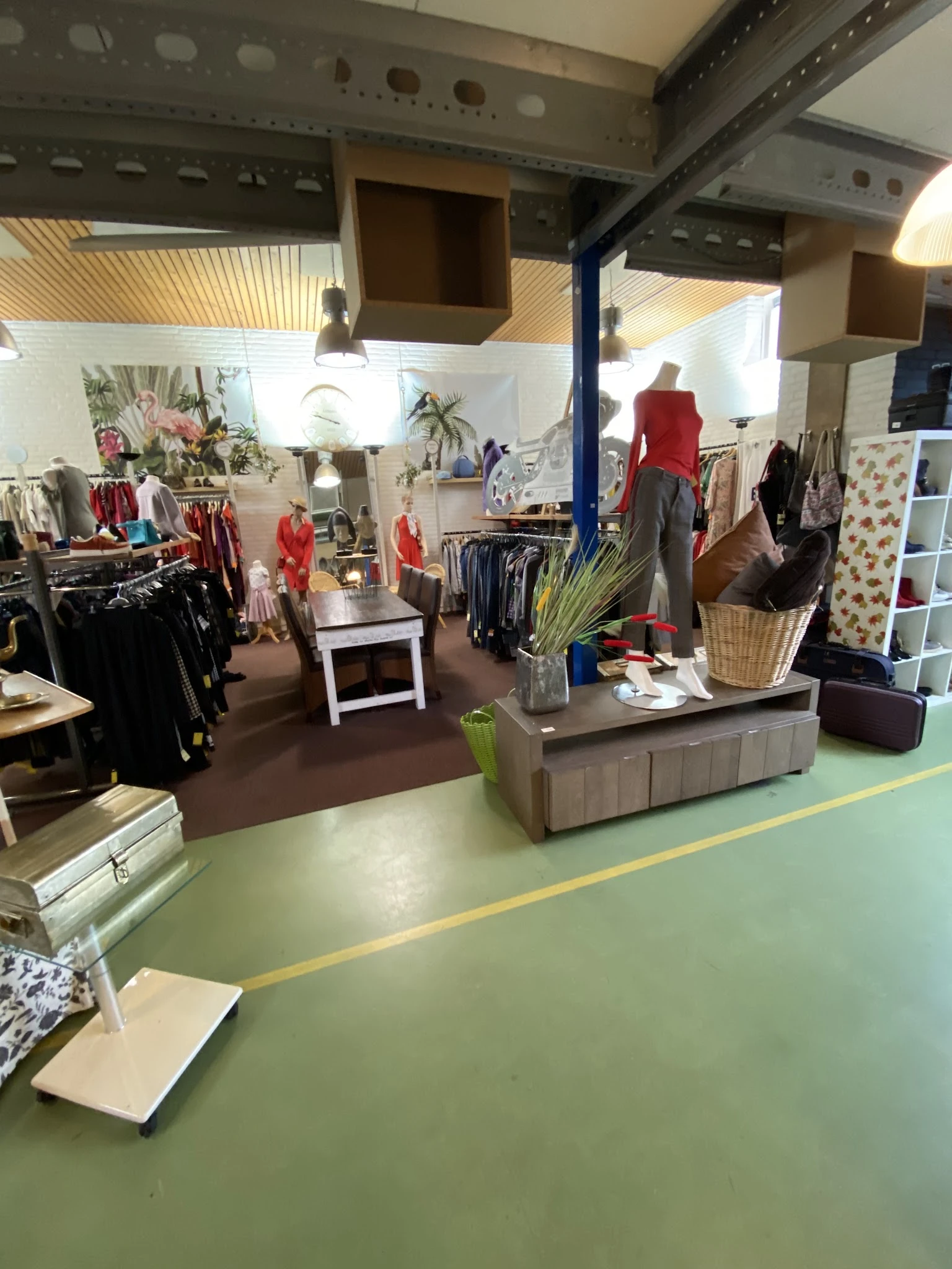 Winkelvloer van kringloopwinkel met kledingrekken, etalagepop in rood shirt, toonbank en stellingen met diverse spullen