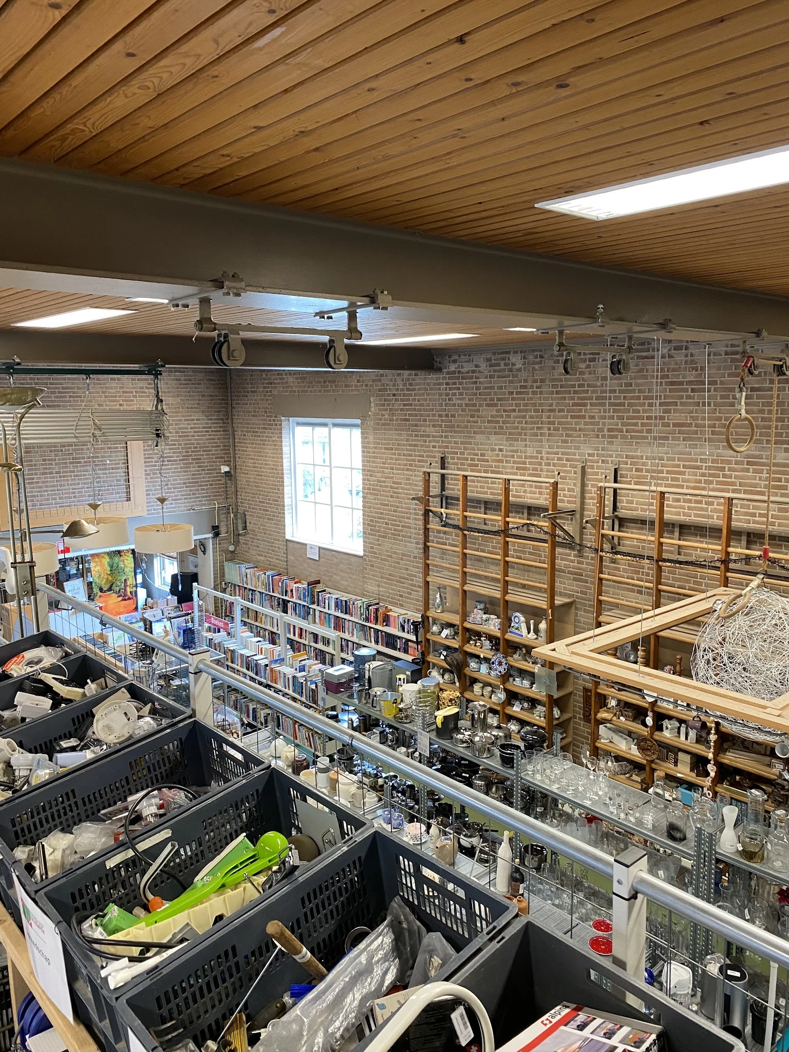 Interieur van kringloopwinkel met boekenrekken, stellingen met spullen en overhead-apparatuur