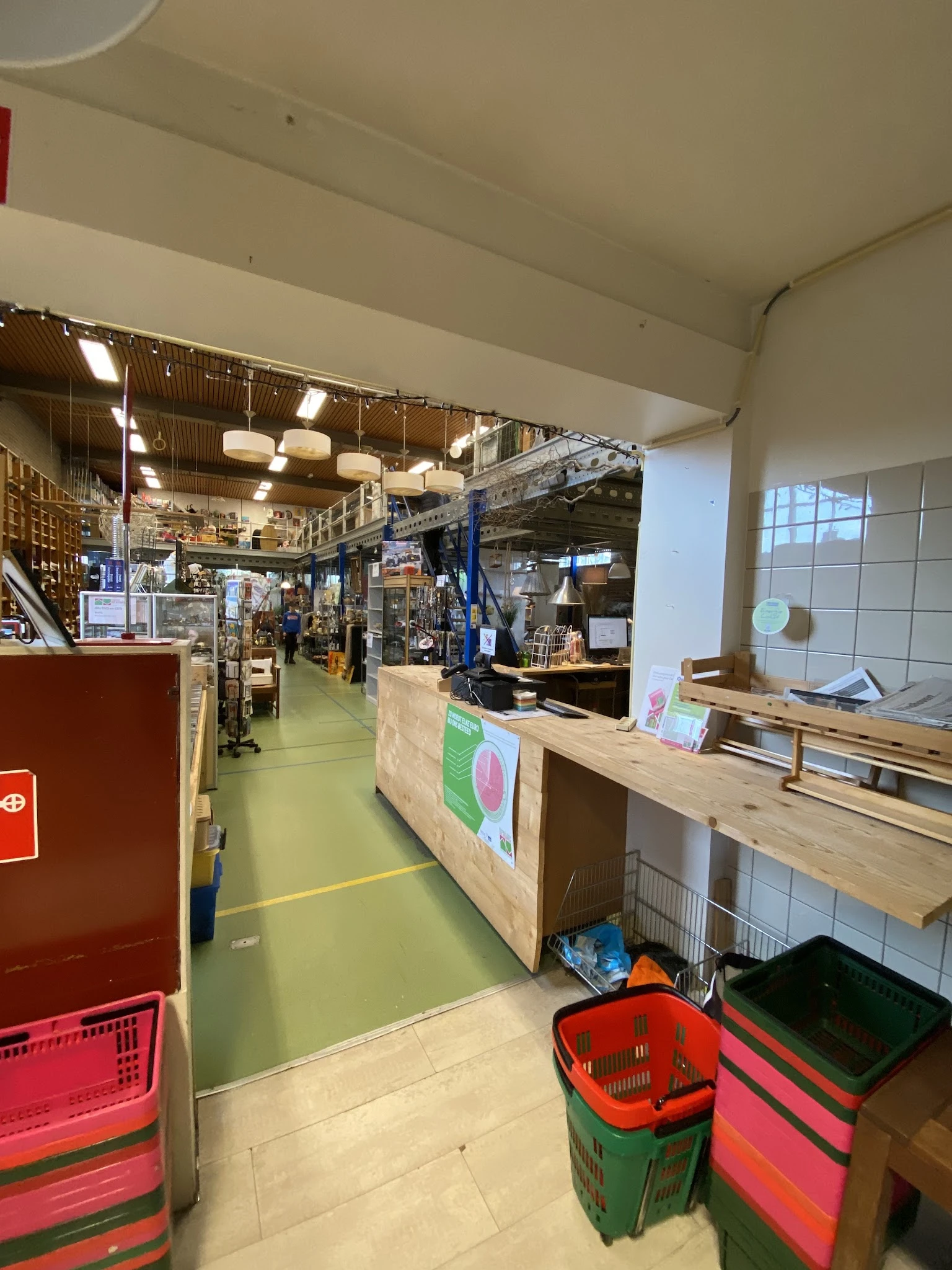 Winkelinterieur met kassa, toonbank en stellingen vol spullen in kringloopwinkel