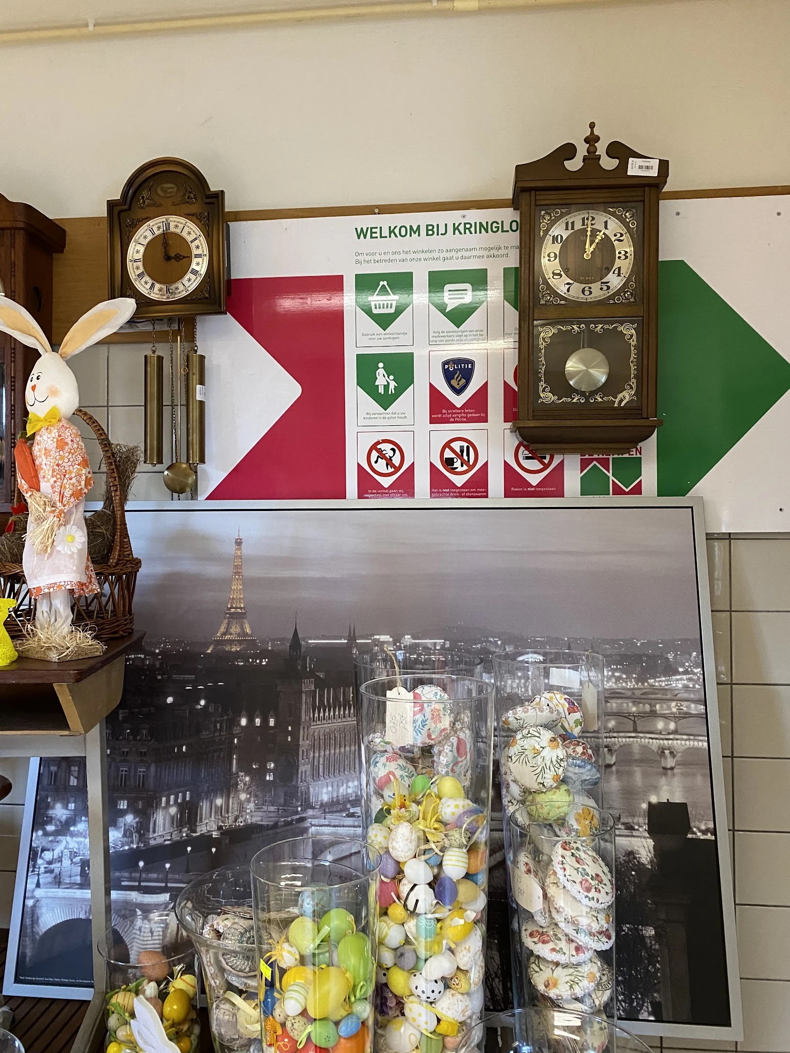 Winkelinterieur met decoratieve items, klokken aan muur, foto van Parijse skyline en paasdecoraties