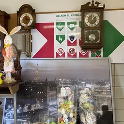 Winkelinterieur met decoratieve items, klokken aan muur, foto van Parijse skyline en paasdecoraties