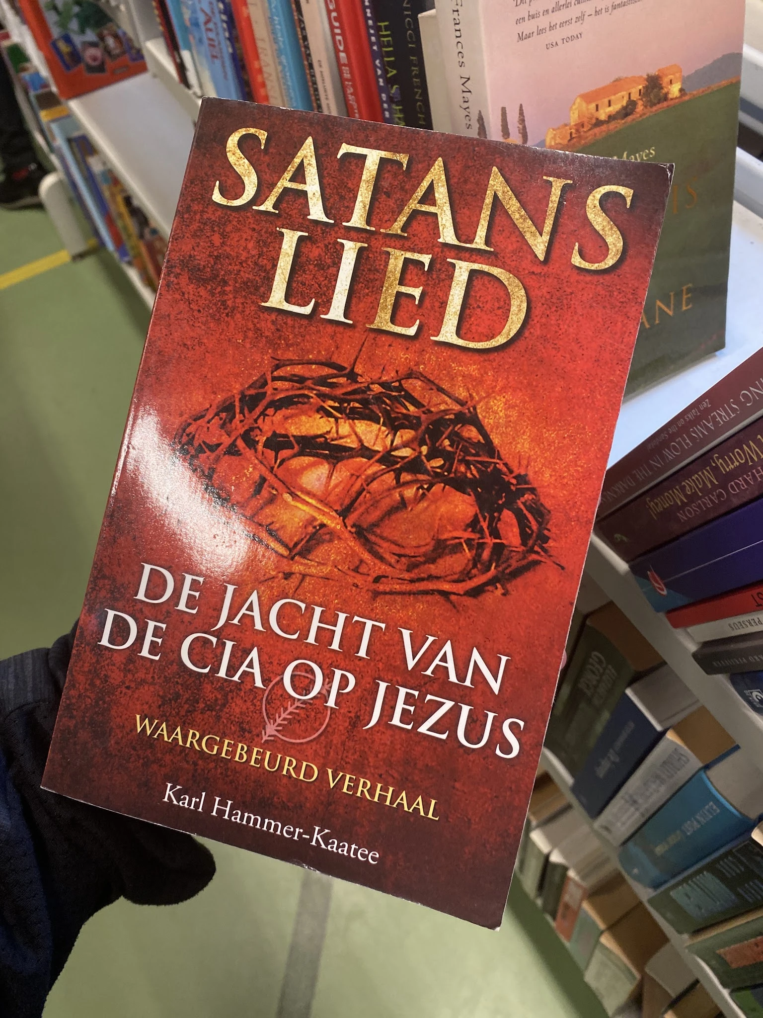 Close-up van een rood boek met gouden letters en een afbeelding van een doornenkroon op de kaft