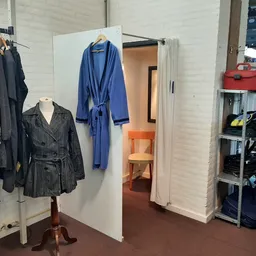 Winkelinterieur met kledingrekken, pashokje en stellingen met tweedehands spullen
