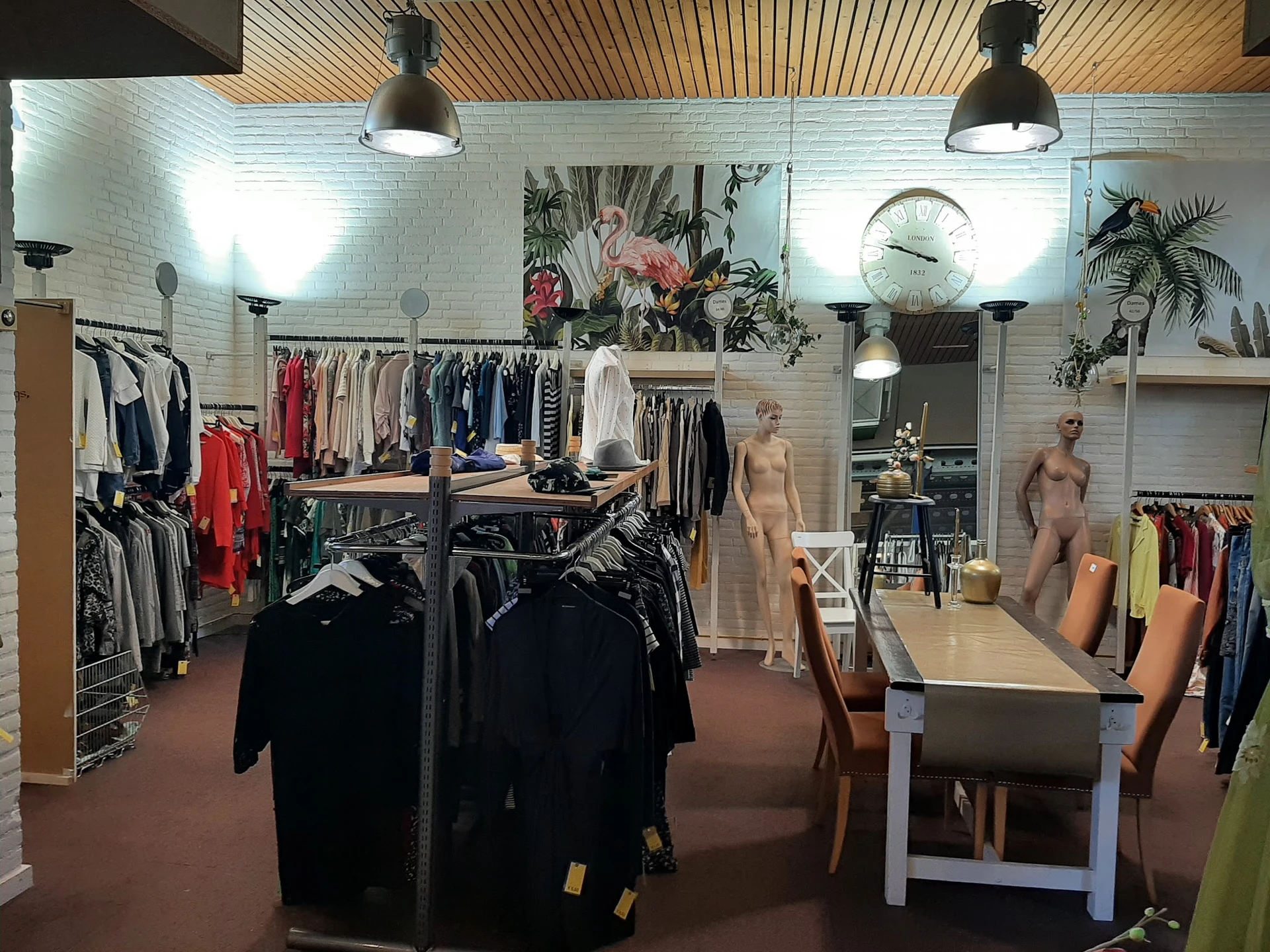 Winkelvloer met kledingrekken, mannekinnen en decoratie in een kringloopwinkel