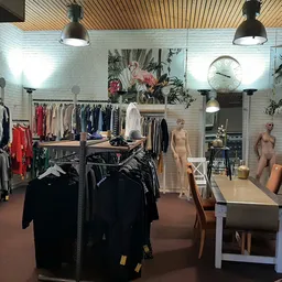 Winkelvloer met kledingrekken, mannekinnen en decoratie in een kringloopwinkel