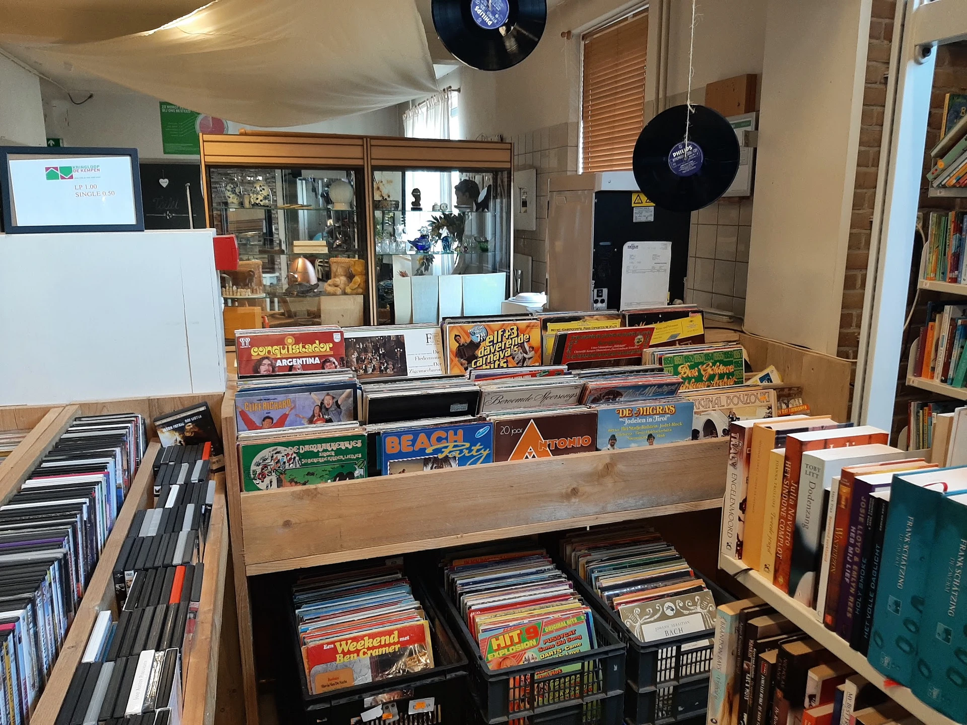 Uitgestalde verzameling tweedehands cd's, vinyl en dvd's in houten stellingen en dozen