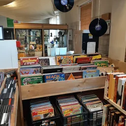 Uitgestalde verzameling tweedehands cd's, vinyl en dvd's in houten stellingen en dozen