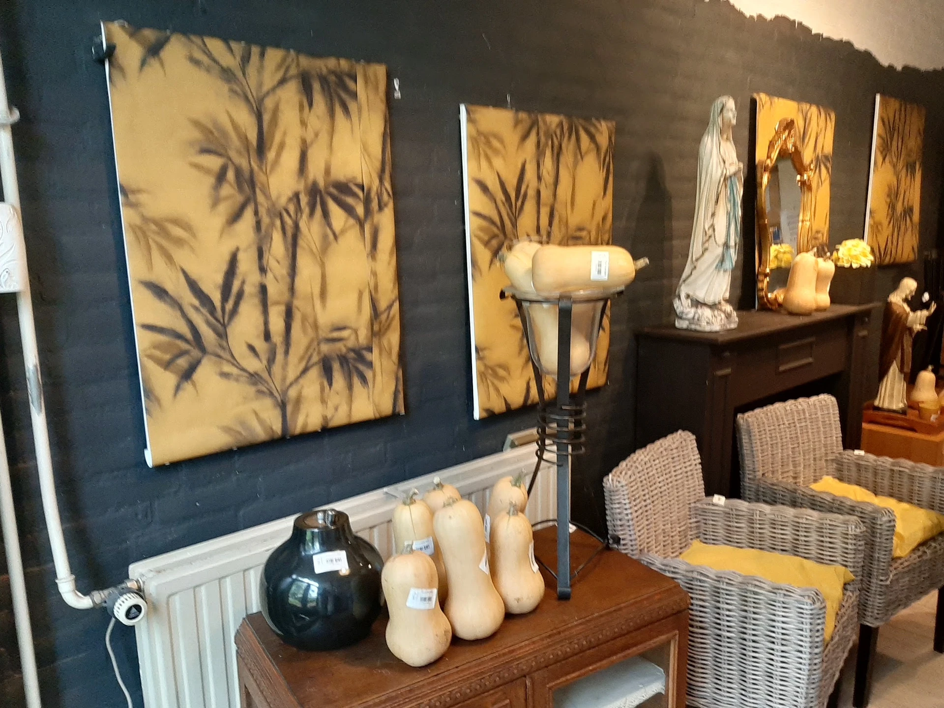 Uitgestalde decoratieve items: kunstdrukken, kaarsen, een zwarte vaas en beeldhouwwerk op een houten tafel