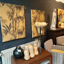 Uitgestalde decoratieve items: kunstdrukken, kaarsen, een zwarte vaas en beeldhouwwerk op een houten tafel