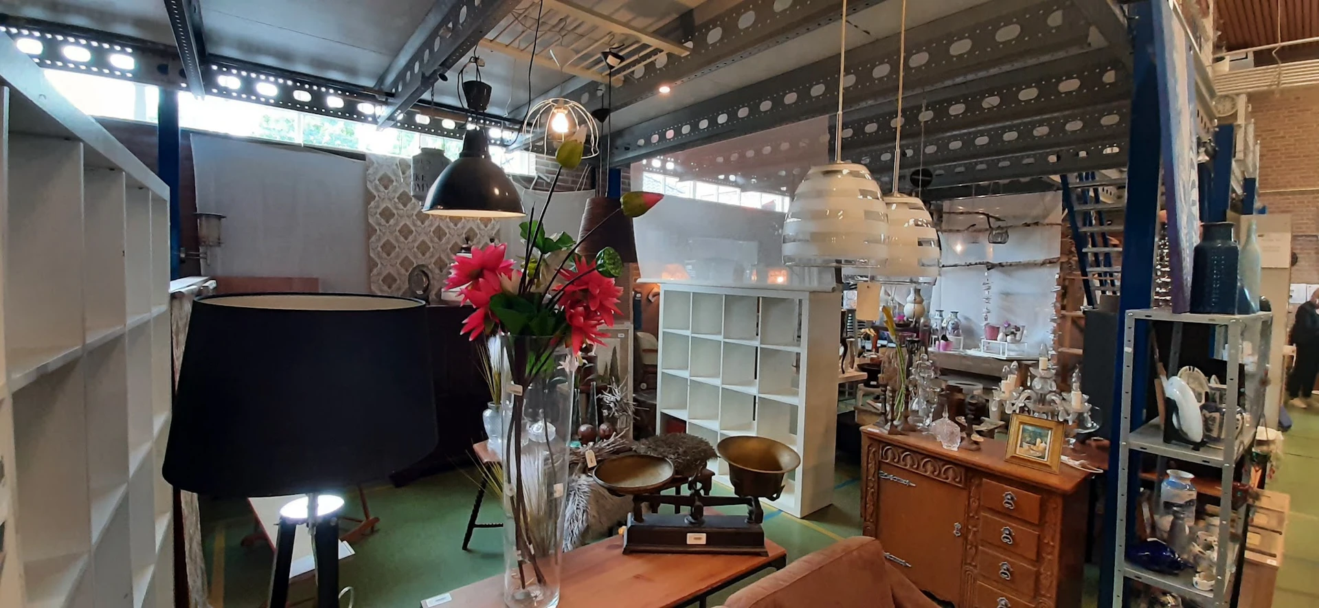 Interieurstukken en decoratie: hangende lampen, bloemen in vaas, weegschaal, houten meubels en stoelen in kringloopwinkel