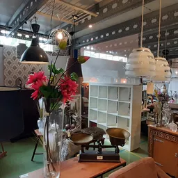 Interieurstukken en decoratie: hangende lampen, bloemen in vaas, weegschaal, houten meubels en stoelen in kringloopwinkel