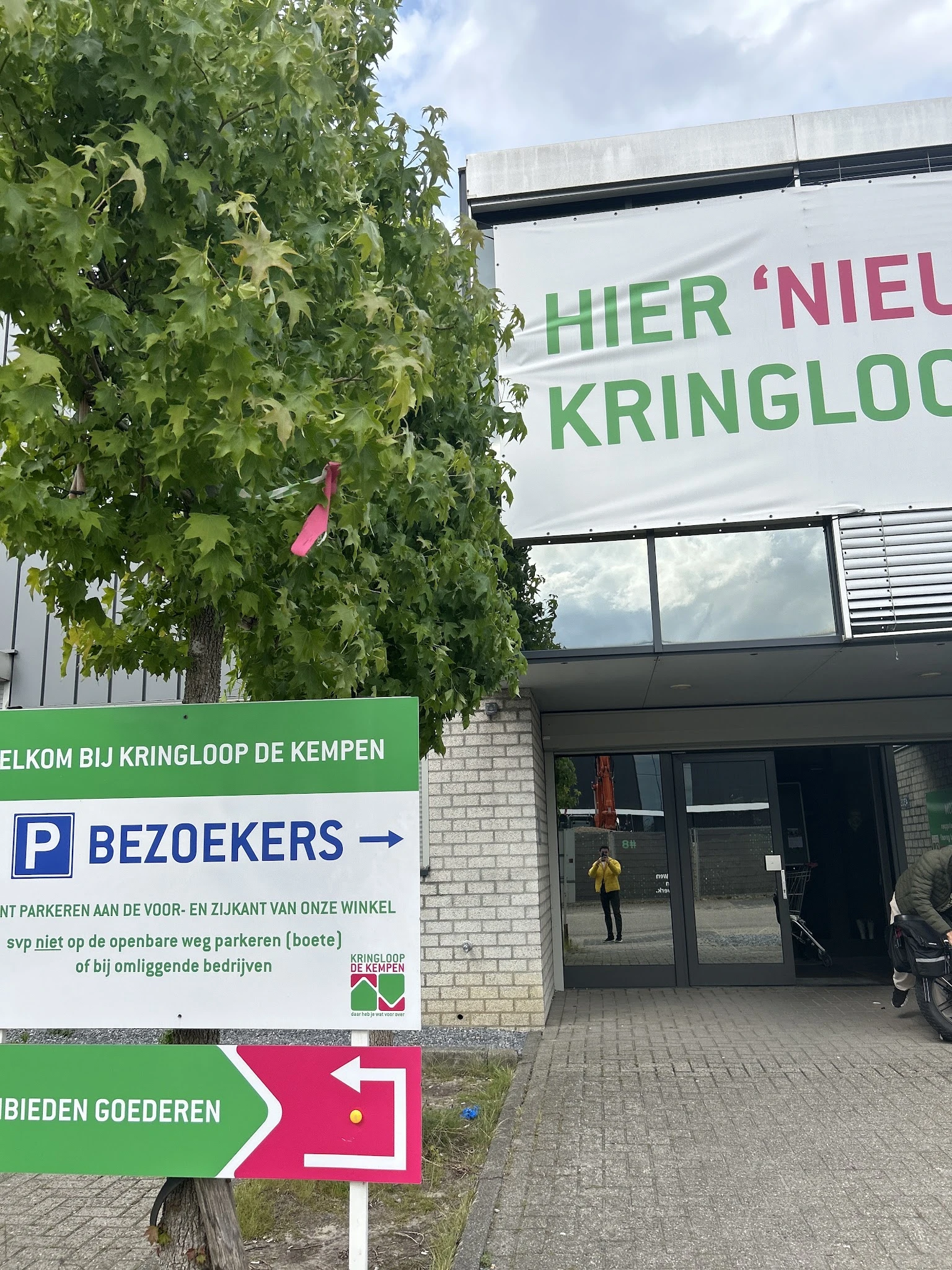 Winkelvoorgevel met groene klimop, parkeerbordje en ingang met glazen deuren