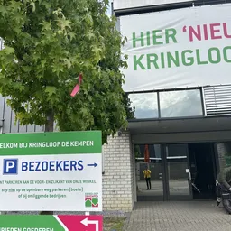 Winkelvoorgevel met groene klimop, parkeerbordje en ingang met glazen deuren