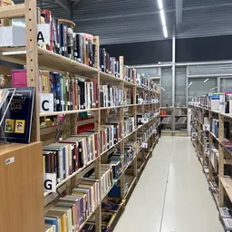 Boekenkasten met boeken gesorteerd op alfabet in een kringloopwinkel, met gangpad in het midden