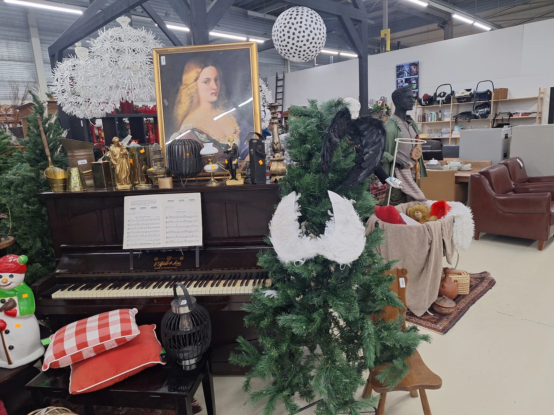 Interieur van kringloopwinkel met een zwarte vleugel, kerststukken, groene slinger en diversen inrichtingsartikelen