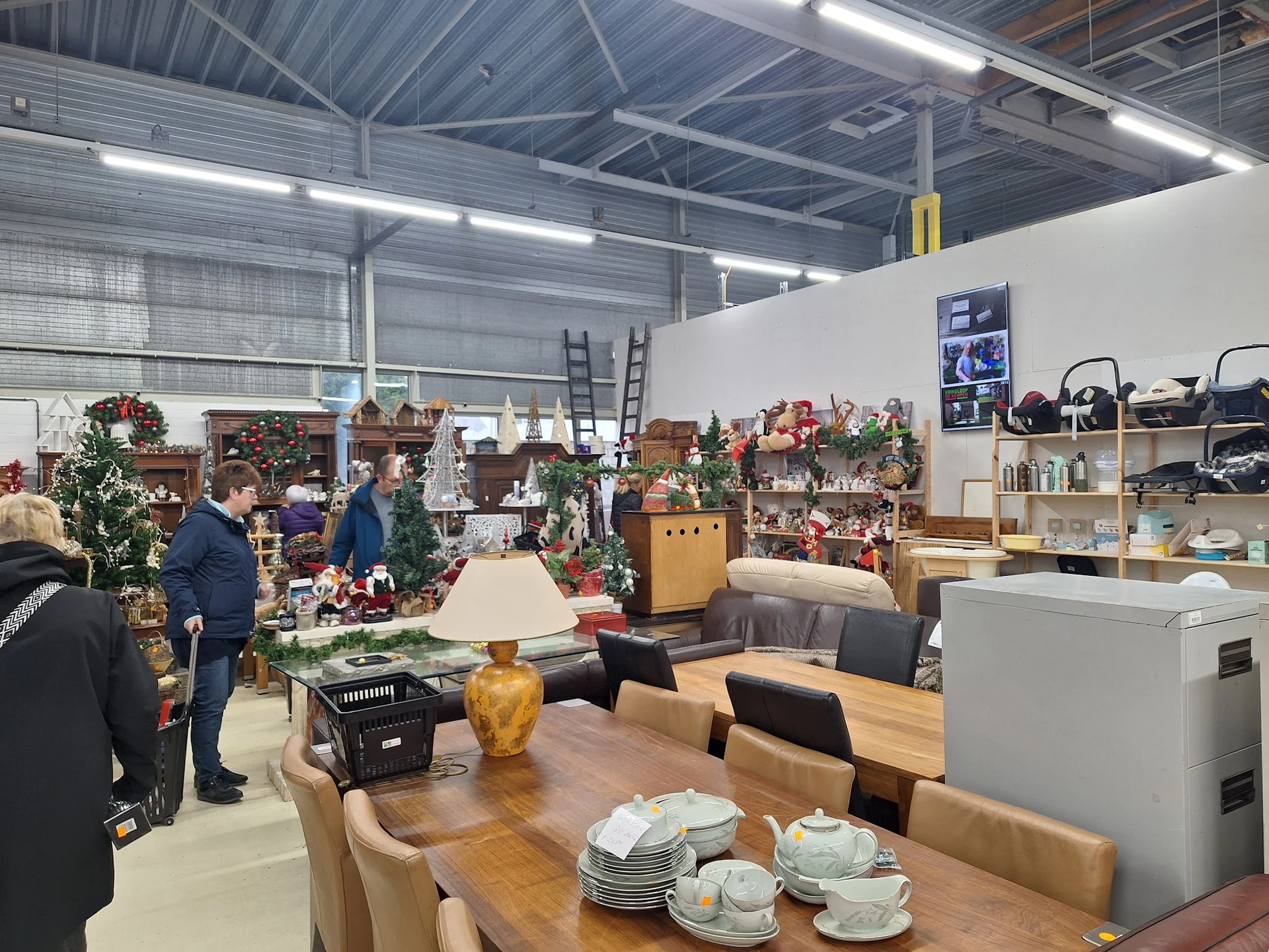 Ruim winkelinterieur met houten eettafel, stoelen, servies, kasten en diverse inboedelspullen uitgestald