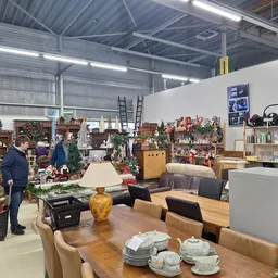 Ruim winkelinterieur met houten eettafel, stoelen, servies, kasten en diverse inboedelspullen uitgestald