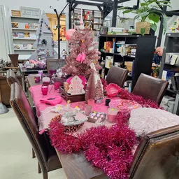 Tafel met roze decoraties, kaarsen en sieraden in kringloopwinkel