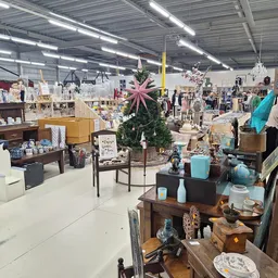 Overzicht van de kringloopwinkel met meubels, decoratie, servies en huishoudelijke artikelen uitgestald op verschillende nive