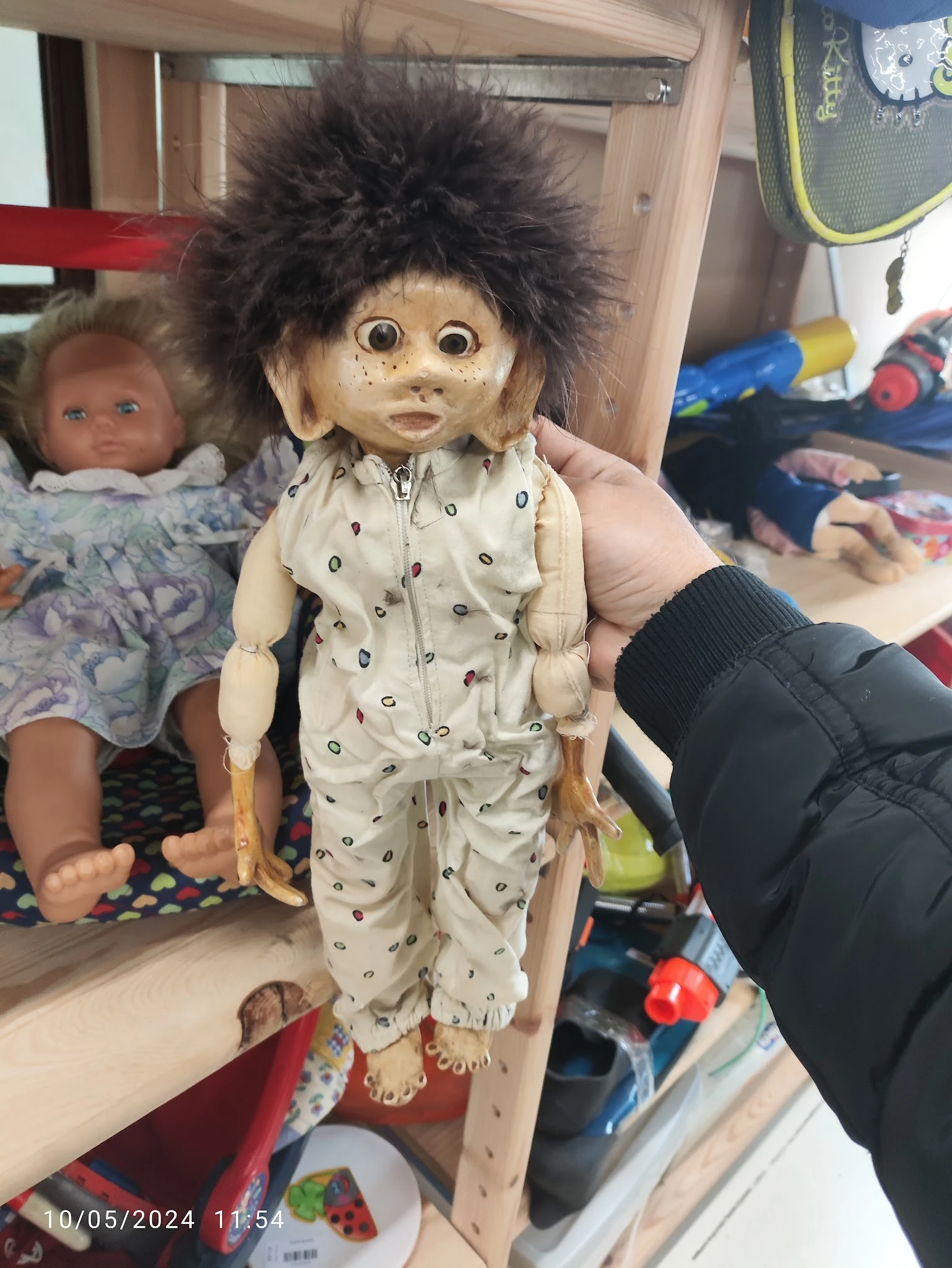 Pop met donker haar in beige pyjama met printje, vastgehouden door hand