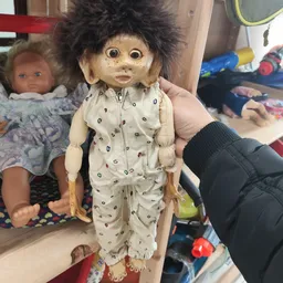 Pop met donker haar in beige pyjama met printje, vastgehouden door hand