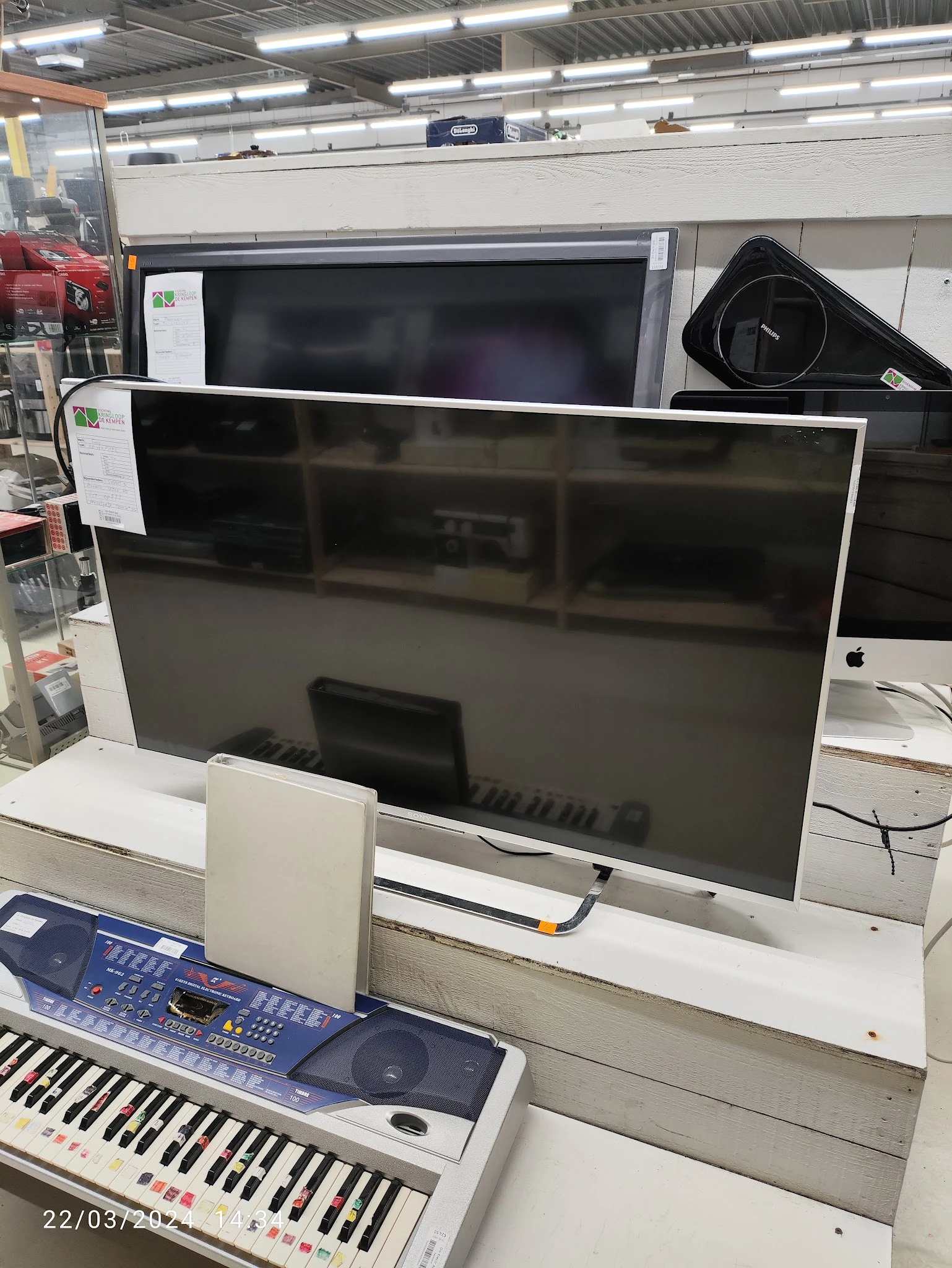 Grote flatscreen televisie met witte rand op display in tweedehands winkel