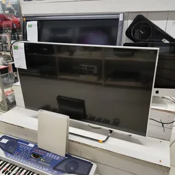Grote flatscreen televisie met witte rand op display in tweedehands winkel