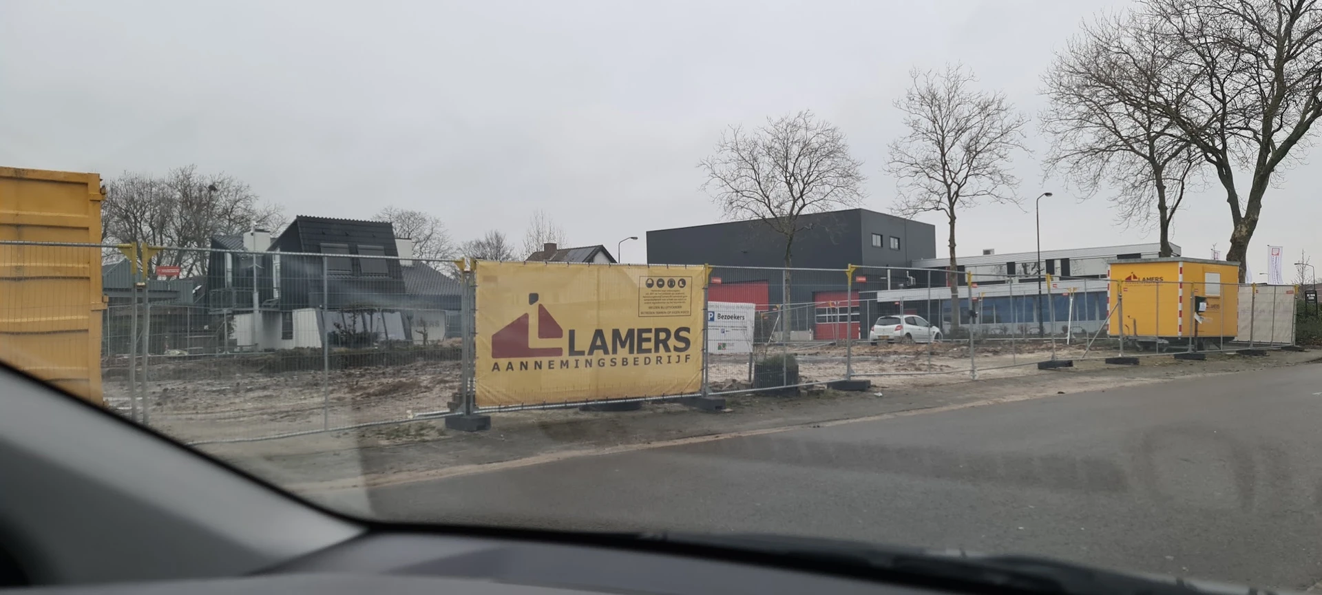 Gele bedrijfsbord van Lamers Aannemingsbedrijf voor een pand met bouwmateriaal op het terrein