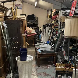Rommelige werkplaats of opslagruimte met diverse spullen, gereedschap en meubels door elkaar