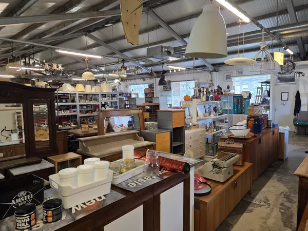 Ruim interieur van kringloopwinkel met houten meubels, tafels en kastjes volgesteld met spullen