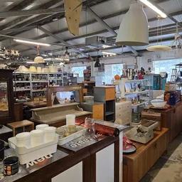 Ruim interieur van kringloopwinkel met houten meubels, tafels en kastjes volgesteld met spullen