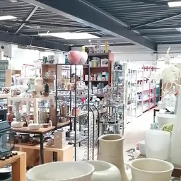 Overzicht van de winkelruimte met kasten, rekken en uitgestal artikelen onder industrieel plafond