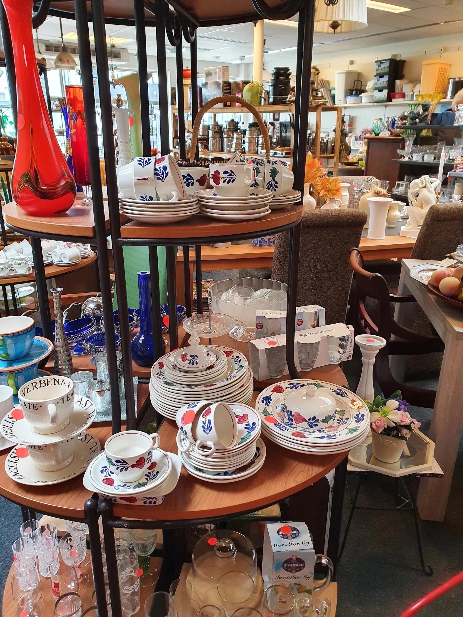 Uitgestalde serviesgoed met blauwe decoratieve motieven, stapels borden, kopjes en glazen op houten tafels