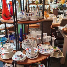 Uitgestalde serviesgoed met blauwe decoratieve motieven, stapels borden, kopjes en glazen op houten tafels