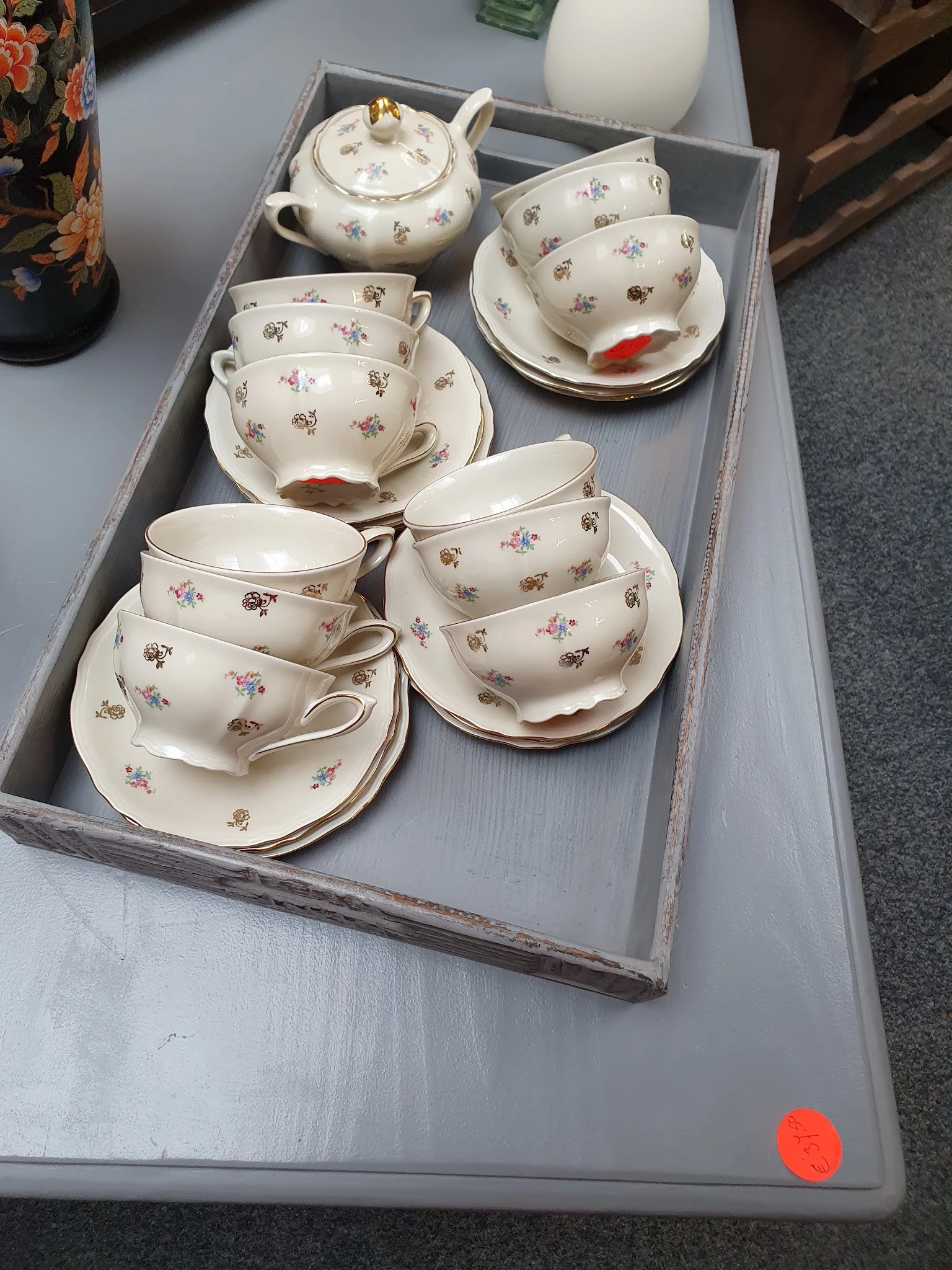 Verzameling vintage theekopjes en schotels met bloemmotieven op grijze dienblad