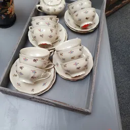 Verzameling vintage theekopjes en schotels met bloemmotieven op grijze dienblad