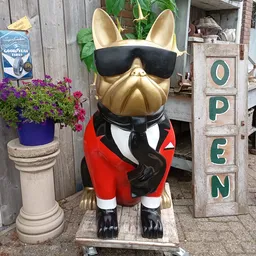 Gouden etalagepop in rode jasje en zonnebril, buiten voor de winkel met bloemen en OPEN-bord